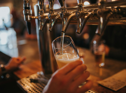 A pint being poured from a tap in a warmly lit pub