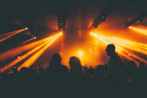 Silhouettes of people dance in a club under golden lights.