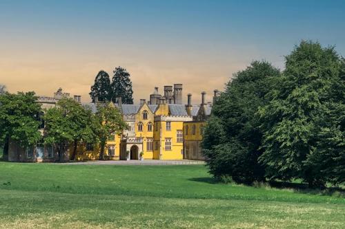 Sweeping lawns lie before a grand yellow building on the Oldbury Court Estate