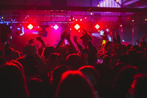 Crowds of people dance at a Parisian club under red and purple light.