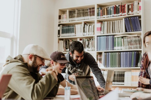 Several male students laugh together over a study group session.