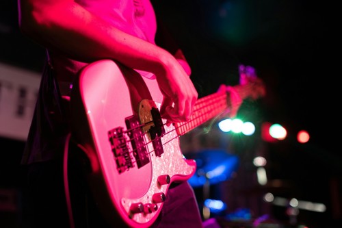 A close-up of an electric guitar player under pink lighting.