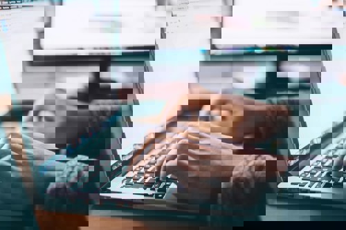 hands typing on a laptop from the left hand side