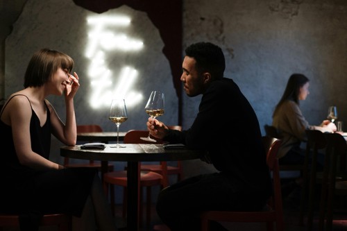 A young man and woman laugh and talk together over drinks on a date.