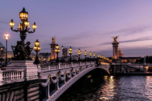 A beautiful Parisian bridge at dusk under a lilac sky.