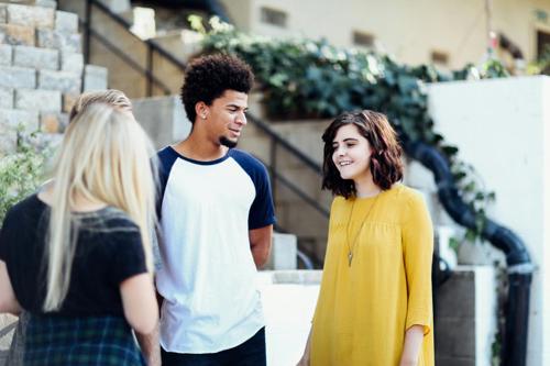 Two girls and two boys stand in a group and get to know each other on campus.